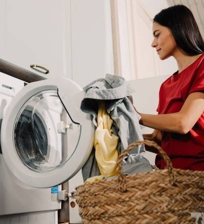 Young,Hispanic,Brunette,Woman,Putting,Clothes,At,Washing,Machine,While
